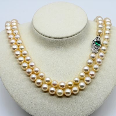 Los Nr. 041 Lange Akoya-Perlenkette mit weißgoldenem Schloss mit Smaragd-Cabochon und Diamantenbesatz, zus. ca. 0,7 ct, 70er Jahre